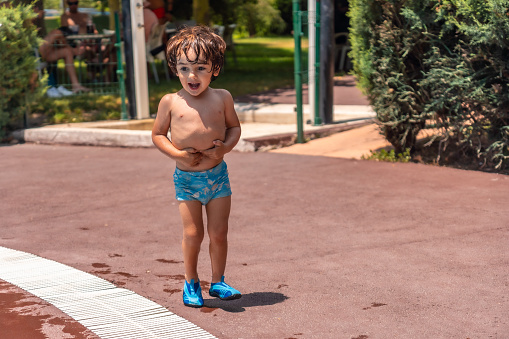 Two year old boy enjoying the summer in a swimming pool, laughing a lot on vacation