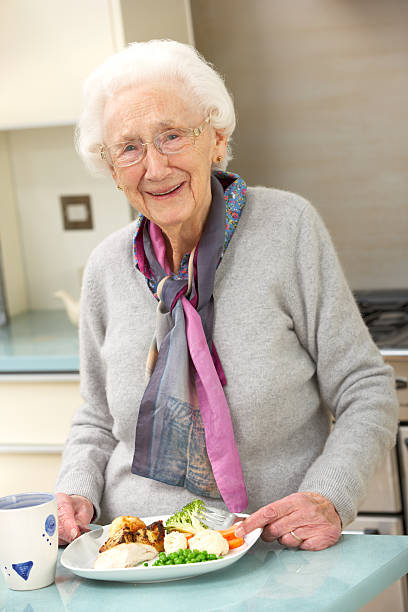mujer mayor disfrutando de una comida en la cocina - one person lifestyles 80 plus years indoors fotografías e imágenes de stock