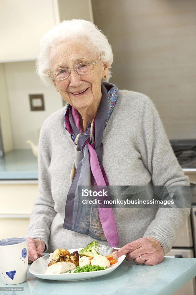Senior woman enjoying meal in kitchen Senior woman enjoying meal in kitchen smiling Senior Adult Stock Photo