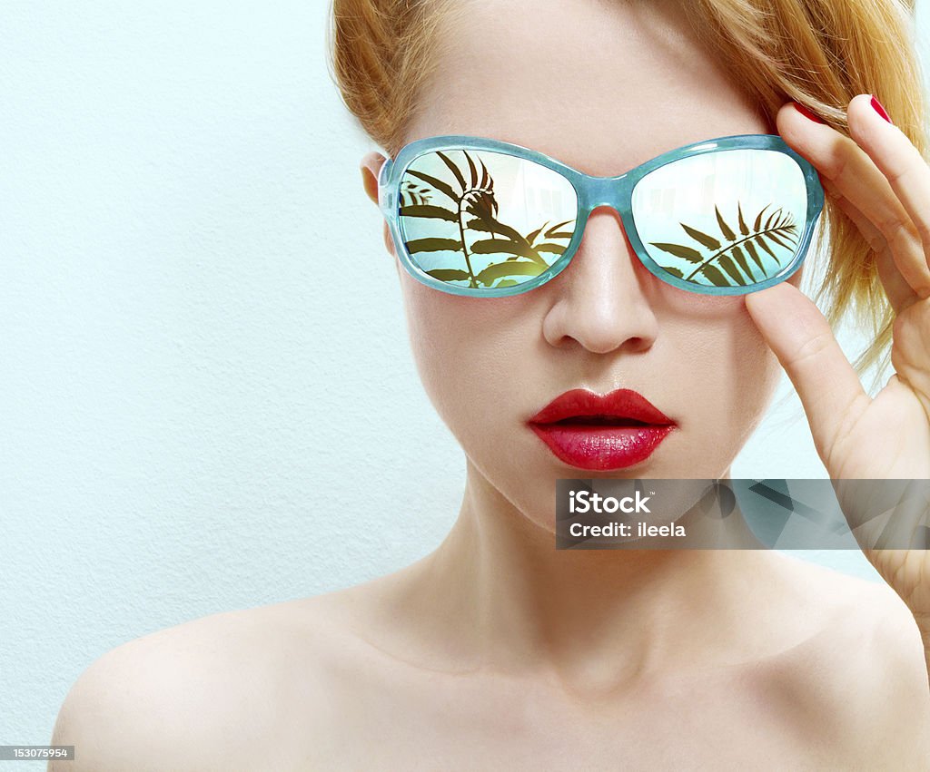 summertime close-up of a beautiful woman with sunglasses on light blue background Light Blue Stock Photo