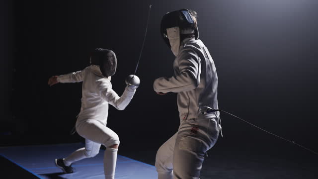 Two professional fencers in combat. Dunking to dodge and landing a hit