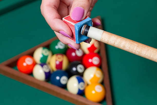 A hand impregnating the billiards' cue tip with the chalk