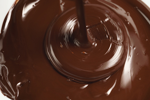 pouring melted premium dark chocolate from above sweet food background