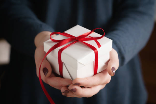 istock young female hands holding gift box with red ribbon 1530776976