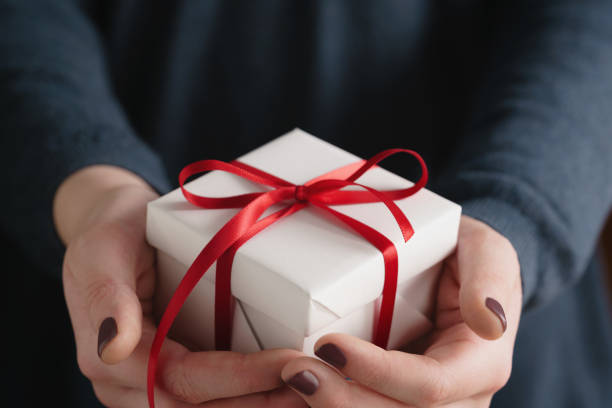 istock young female hands holding gift box with red ribbon 1530778067