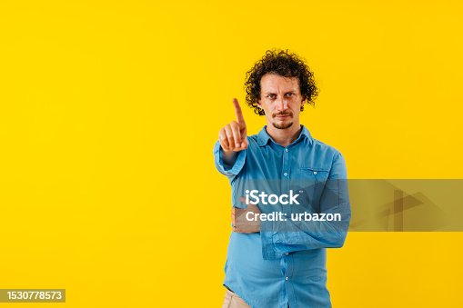 istock Displeased Young Man Waving His Finger In Front Of A Yellow Wall 1530778573