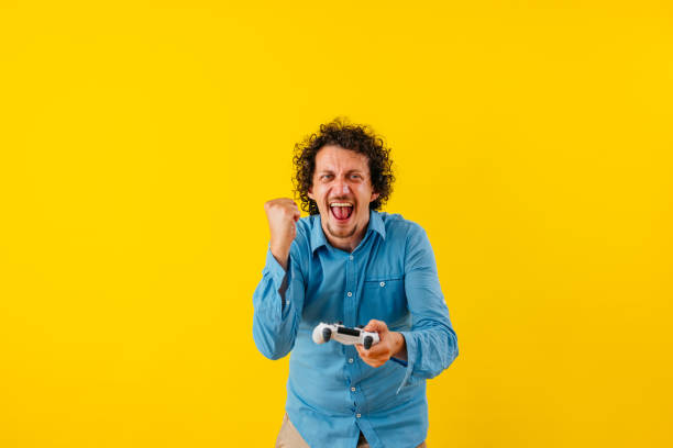 istock Happy Young Man Playing A Video Game In Front Of A Yellow Wall 1530778826