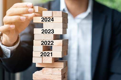 2024 year Goals, Business planning, Risk Management, Solution and strategy Concepts. Businessman hand placing or pulling wooden block on the tower