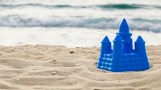 A vibrant blue plastic castle on a sandy beach.