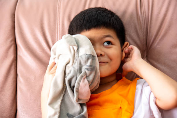 istock A smiling little boy play with doll on sofa at his home. 1530808404