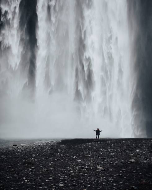 istock Lonely person standing in front of a cascading waterfall 1530808773