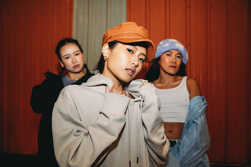 Portrait of three fashionable young adult women looking at camera. Badass pose of three hip hop dancers wearing cool street style clothes.