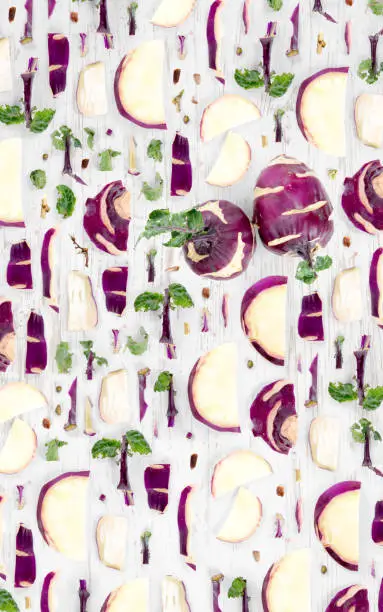 Abstract background made of Kohlrabi vegetable pieces, slices and leaves on wooden background.