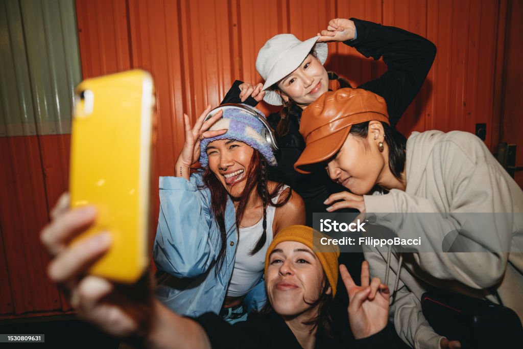 Junge erwachsene Frauen, die coole Streetstyle-Kleidung tragen, machen nachts ein Selfie - Lizenzfrei Generation Z Stock-Foto