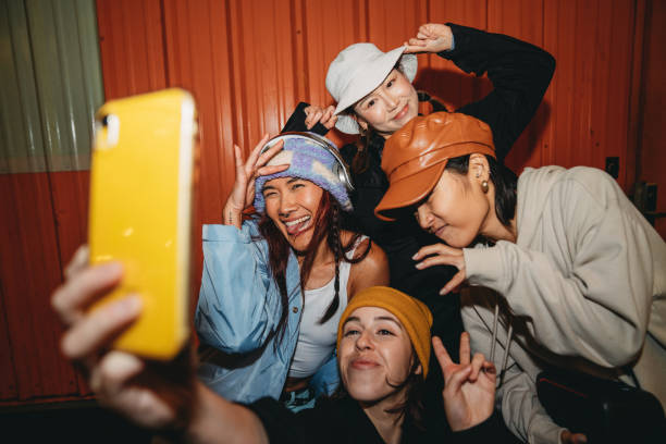 Young adult women wearing cool street style clothes are taking a selfie at night Young adult women wearing cool street style clothes are taking a selfie at night. They are wearing hats. Hip hop dancers. stylish selfie stock pictures, royalty-free photos & images