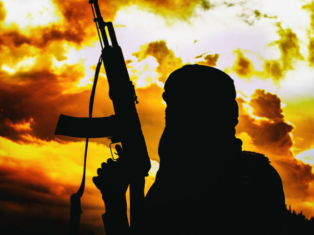Muslim militant with rifle in the desert on sunset with AK rifle stock photo