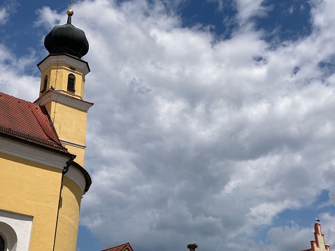 A close-up view of a majestic church bell tower surrounded by a cloudy sky