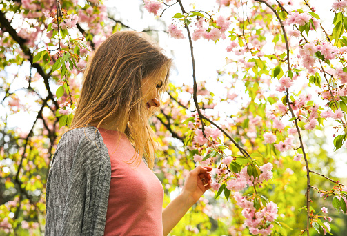 Beautiful girl near blooming tree. Blossom sakura outdoors.  Spring mood. Woman relaxing.