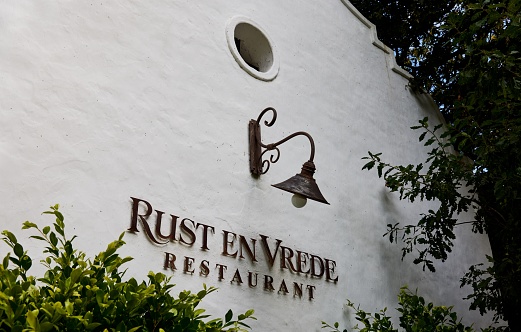 Stellenbosch, South Africa – January 26, 2023: The wall of Rust en Vrede Wine Estate with an old lamp and lettering.