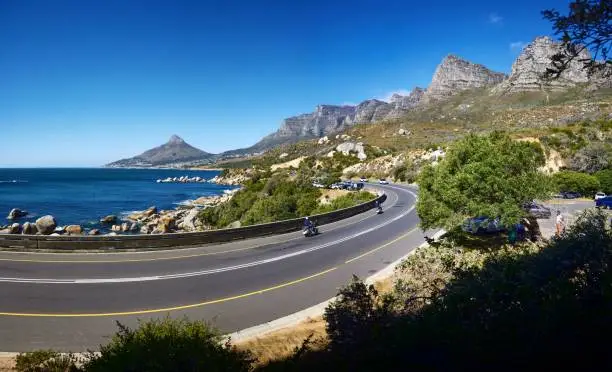 A curvy road surrounded by mountains. Lionshead and the Atlantic Ocean in Cape Town, South Africa.