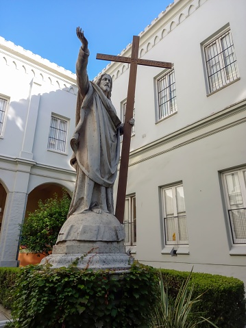 Buenos Aires, Argentina – April 30, 2023: Statue of Jesus Christ with the cross pointing the sky with his hand in the garden of St. Felicitas School, Barracas district, Buenos Aires, Argentina