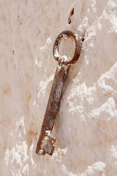rusty key on a rustic white stone wall stock photo