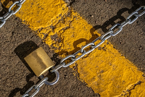 A yellow curb with two heavy chains securely held together with a padlock