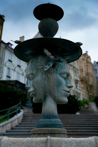 A vertical shot of a The Faces Fountain in Karlovy Vary under the blue sky