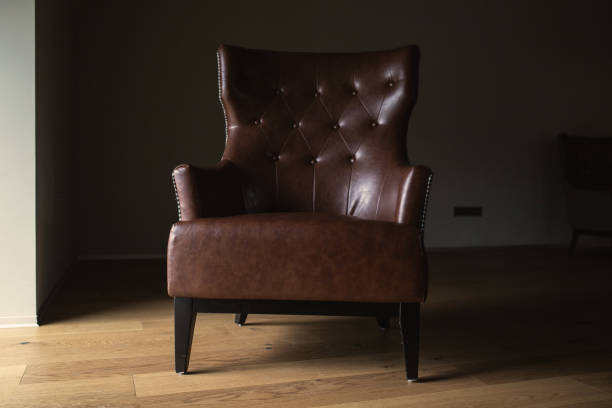 istock Brown leather armchair in an empty dark room by the window 1530886065