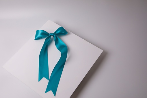 A gift card with a blue ribbon tied around it atop a solid white background