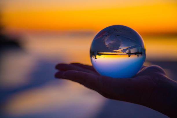 istock Person's hand holding a crystal ball against a sunset background 1530897831