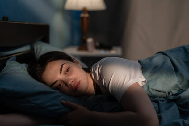 Young sad woman lying in bed late at night trying to sleep suffering insomnia. Girl in bed scared on nightmares looking worried and stressed. Sleeping disorder and insomnia Young sad woman lying in bed late at night trying to sleep suffering insomnia. Girl in bed scared on nightmares looking worried and stressed. Sleeping disorder and insomnia concept insomnia stock pictures, royalty-free photos & images