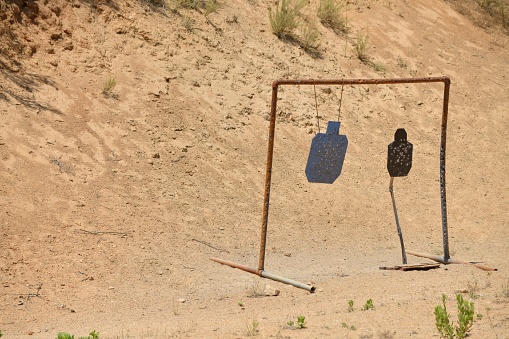 The targets at a shooting range set up in a desolate outdoor area illuminated by bright sunlight
