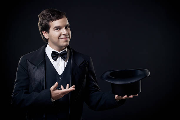 istock magician showing tricks with top hat isolated on dark background 153092185