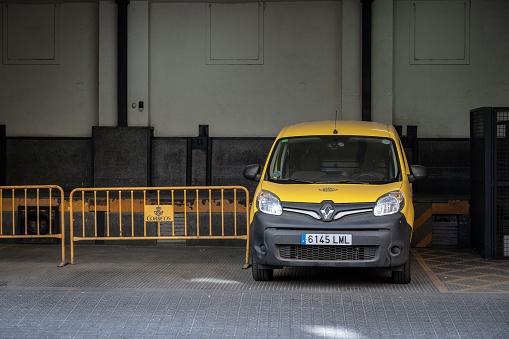 Barcelona, Spain – July 01, 2023: Front view of a modern yellow Renault Kangoo delivery van parked at the post office loading dock