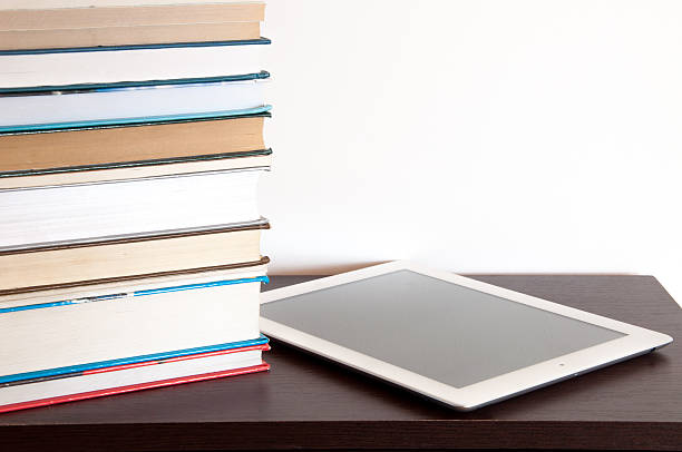 E-book reader and stack of books on a table E-book reader and stack of books on a table kindle and ook stock pictures, royalty-free photos & images