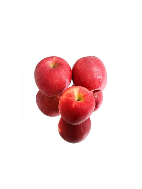A closeup of juicy red apples on a reflective white surface