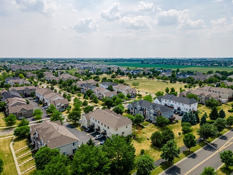 Plainfield, United States – June 22, 2022: An aerial view of a residential area with multiple houses surrounded by green trees. Plainfield, IL.
