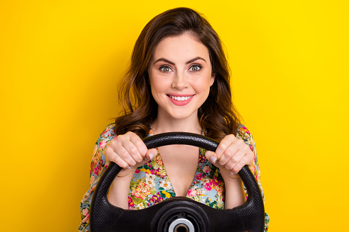 Portrait of lovely positive lady arms hold wheel beaming smile isolated on yellow color background.