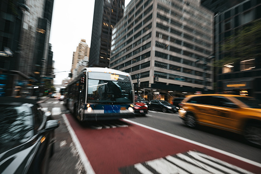 Blurred zoom in effect on traffic in New York midtown Manhattan with bus and taxi passing by.