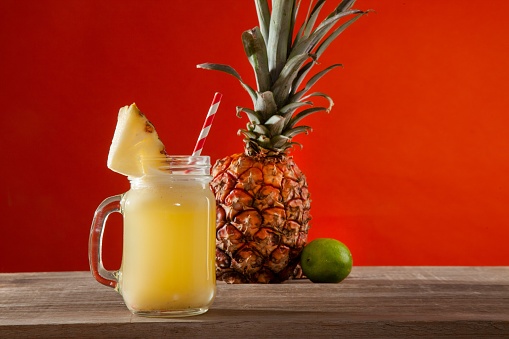 A mason jar filled with refreshing pineapple and lime juice accompanied by a pineapple slice