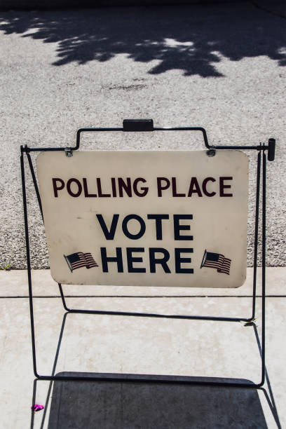istock Temporary standing sign reading Polling Place Vote here with American flags standing on parking lot 1530968466