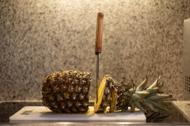 pineapple cut in half on a cutting board and a knife