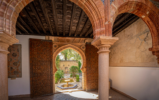 One of the interior patios of El Palacio de Mondragn, a historic Mudejar-Renaissance building located in the old town of Ronda, Malaga, Spain with a door leading to the outside garden