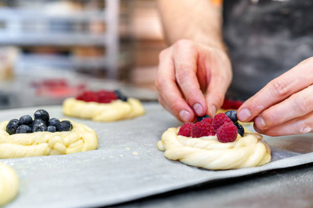 Artisan Baker's Skilled Hands Filling Pastries with Berries, Preparing for Baking