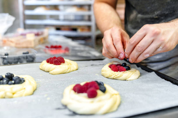 Skilled Baker's Hands: Filling Pastries with Red Currants and Raspberries, Ready for the Oven.