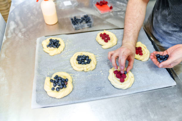 Bakery Worker's Skillful Hands Crafting Berry-Filled Pastries for Baking
