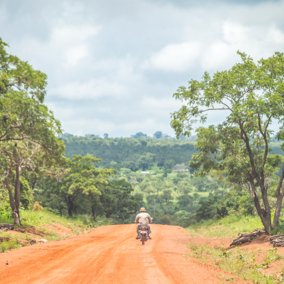 Man with a hat riding motorbike on the road through Tata-Somba.