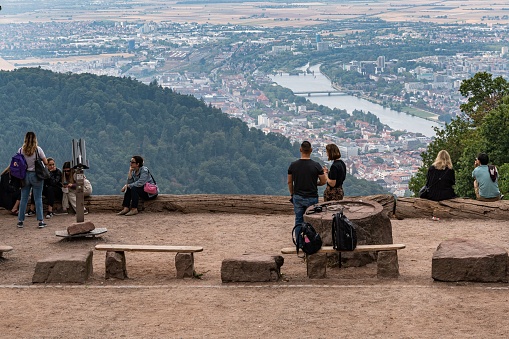 Heidelberg, Germany – August 17, 2022: A closeup of  people enjoying a scenic view of a city from a viewpoint atop a rocky hill in Germany