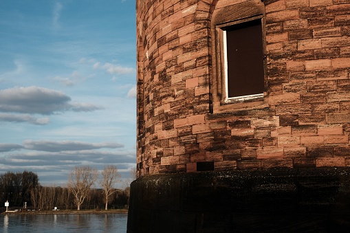 A picturesque scene of a traditional brick structure at the edge of a body of water illuminated by the setting sun